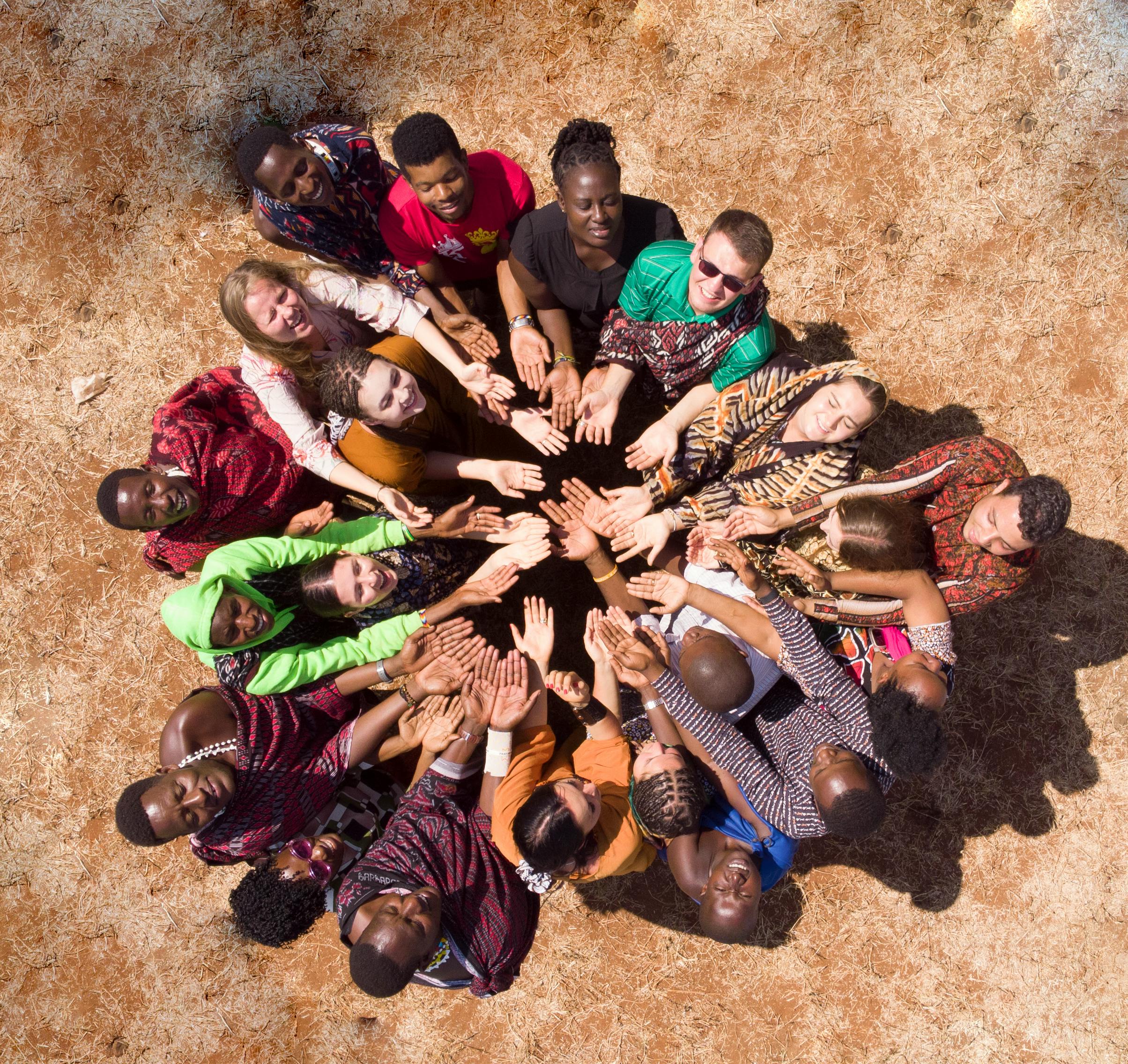 Aerial view of a diverse group in Tanzania symbolizing unity and teamwork by joining hands.