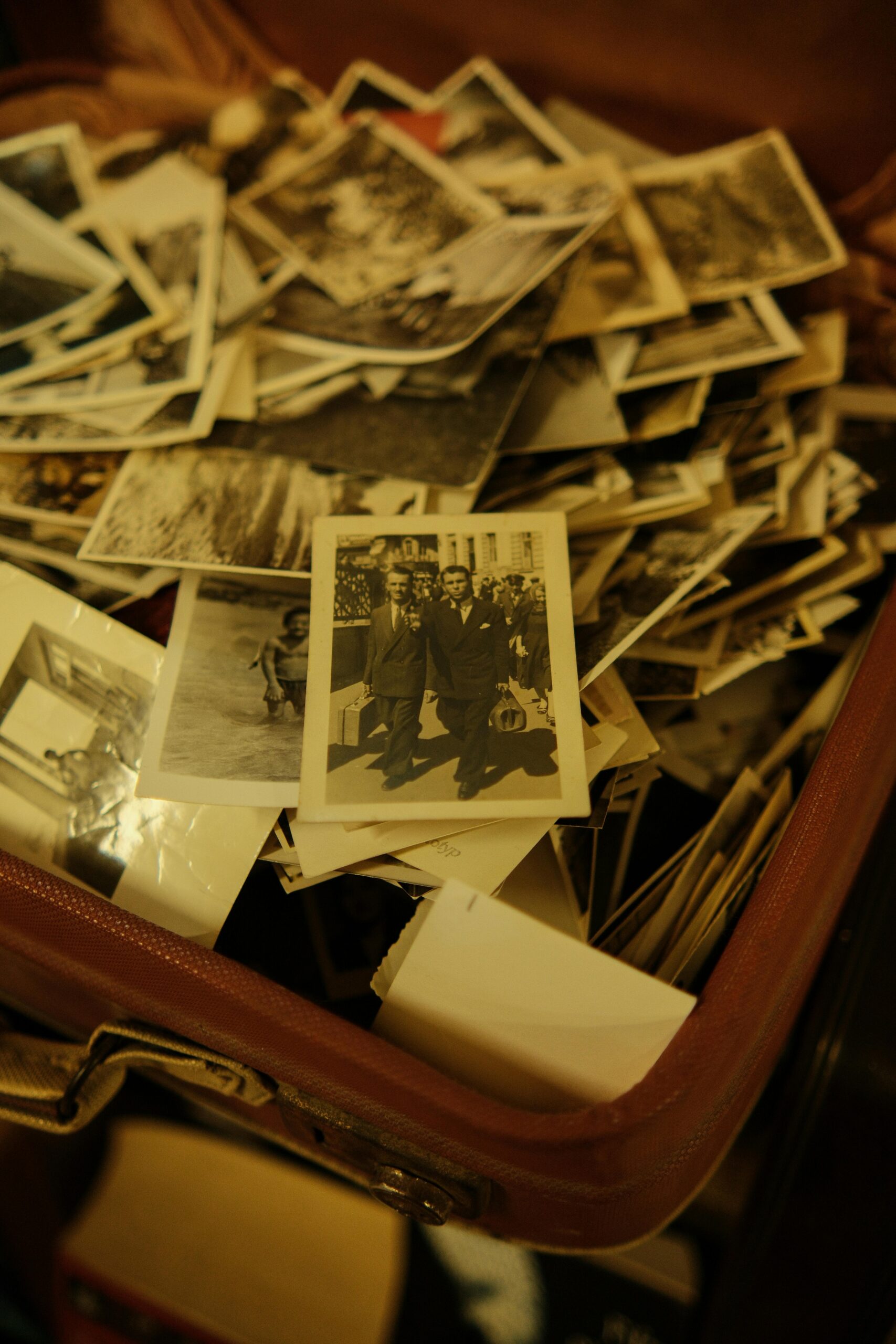 A collection of vintage black and white photographs in an antique suitcase.