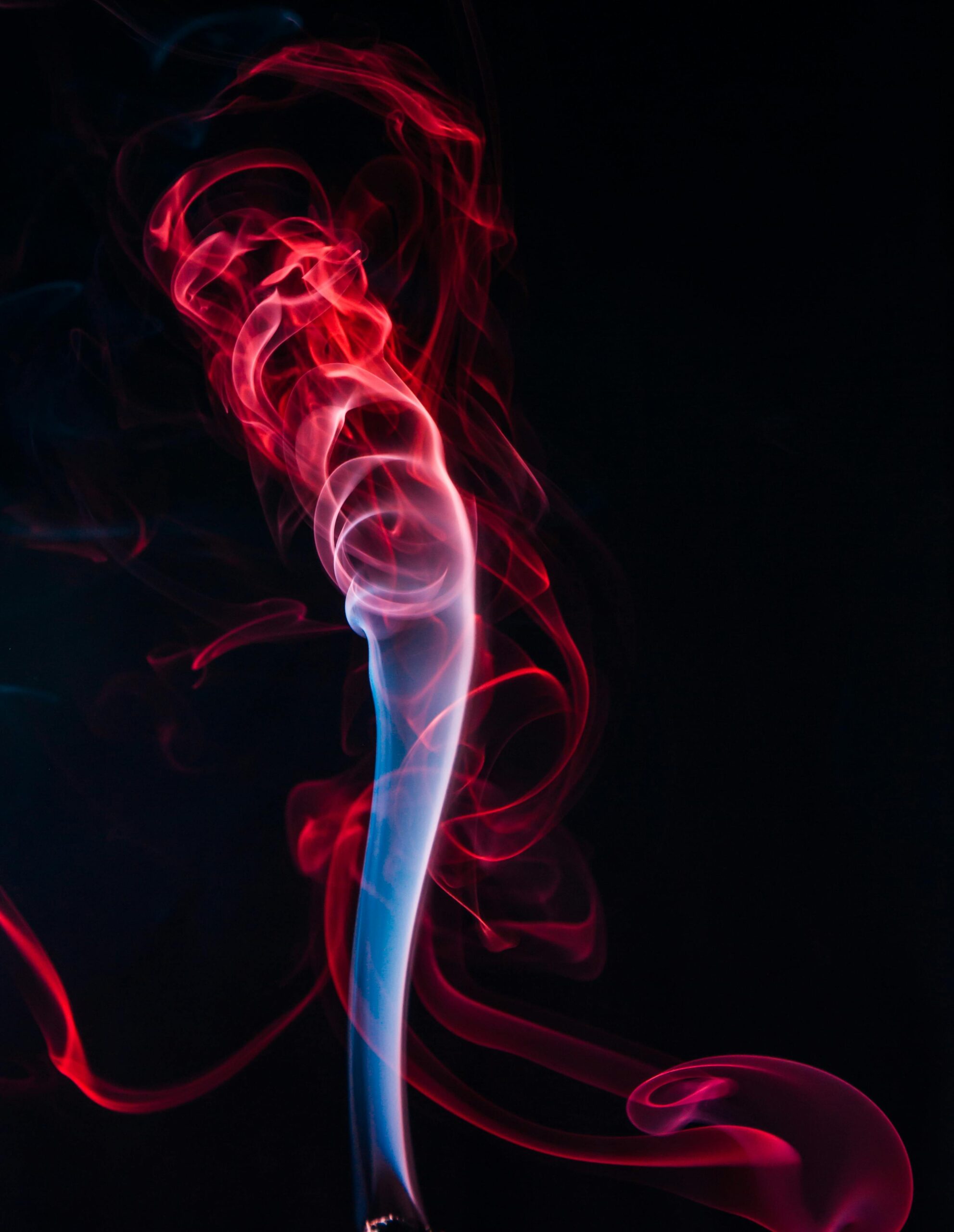 Mesmerizing abstract art showing vibrant red and blue swirling smoke against a dark background.